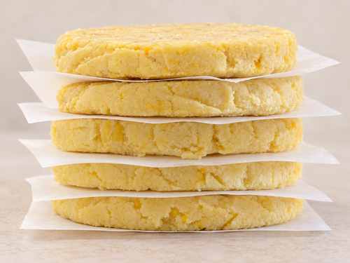 Side view of five uncooked Chocolo arepas separated by parchment paper.